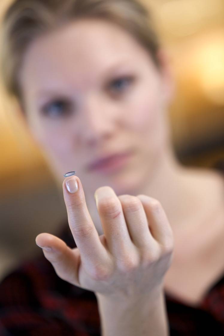 Frau mit Kontaktlinse auf dem Zeigefinger