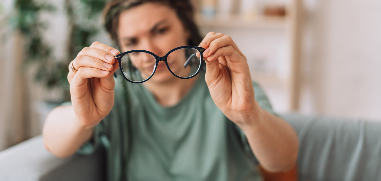 Frau hält Brille von sich weg, Verkleinerung im Brillenglas