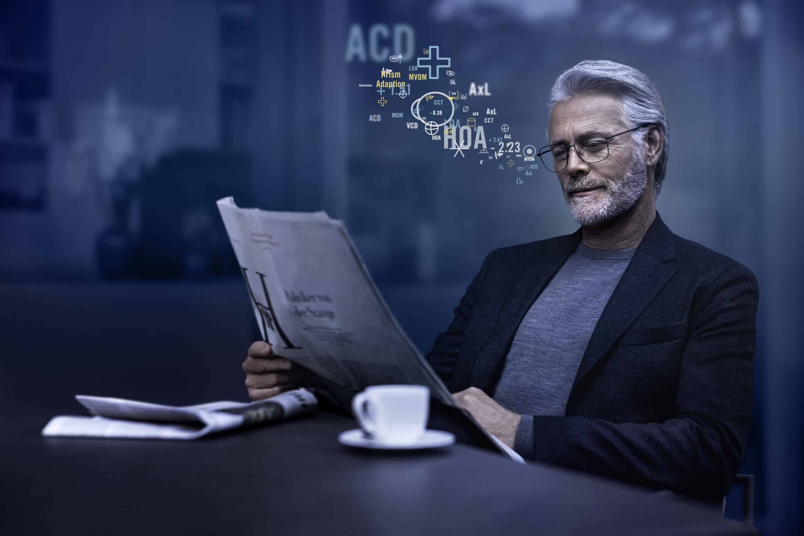Mann mit Gleitsichtbrille liest sitzend eine Zeitung